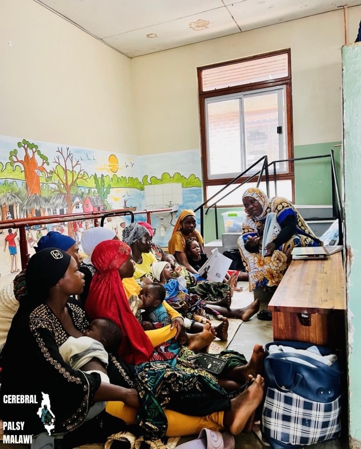 Caregivers and children gathered indoors during a Patsogolo CP Foundation clinic day